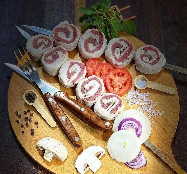 آماده سازی رول‌های کباب گوشت و جگر تازه با سبزیجات پیاز، گوجه‌فرنگی و قارچ برای سیخ‌گیری در جگر سرای عیاران