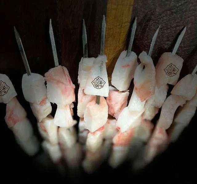 سیخ‌های کباب دنبه و گوشت تازه و باکیفیت، مزین به لوگوی خاص "جگر سرای عیاران". آماده طبخ برای تجربه طعمی عالی از کباب.