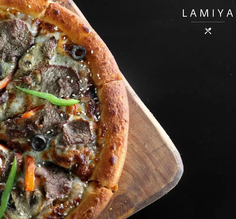 پیتزا گوشت و زیتون خوش‌طعم کافه رستوران لمیاء با خمیر ترد، کنجد و فلفل سبز تازه. تجربه‌ای لذیذ و به‌یادماندنی.