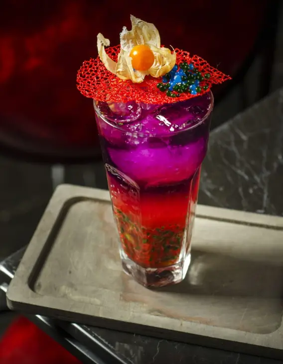 کوکتل لایه ای رنگارنگ و خاص در کافه رستوران ریون، با ترکیب رنگ‌های بنفش، صورتی و قرمز، مناسب برای تجربه‌ای بی‌نظیر.