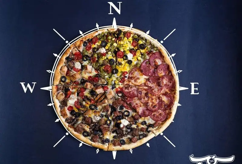 پیتزا چهارفصل جذاب سیب ۳۶۰، با چهار نوع تاپینگ متفاوت و چیدمان هنری شبیه قطب‌نما، مناسب برای سفارش غذای متنوع.