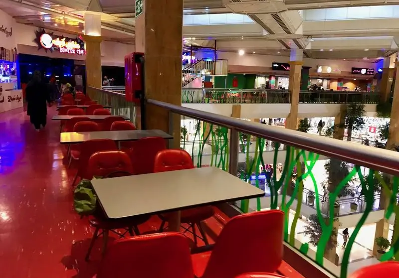 فضای داخلی فودکورت مرکز خرید بزرگ با میز و صندلی‌های قرمز فست فود شیلا، محیطی شاداب و دلنشین برای مشتریان