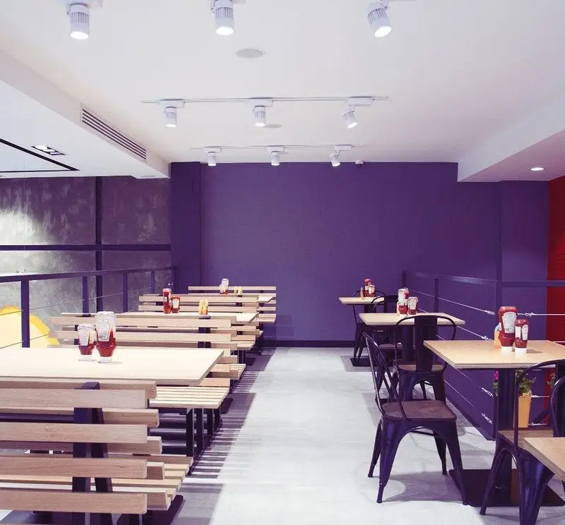 دکوراسیون شیک و جذاب رستوران نانوچی با نورپردازی عالی، دیوارهای بنفش و چیدمان متنوع میز و صندلی‌های راحت و مدرن.