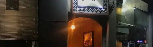 ورودی اصلی کافه سرای لوکس امیران در شب با تابلوی مزین به طرح‌های آبی، نورپردازی گرم و فضایی جذاب و دلپذیر برای مشتریان.
