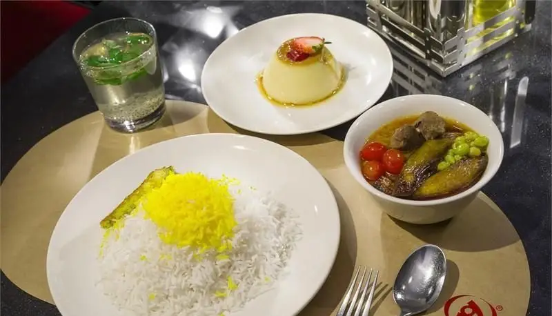 تصویری از غذای ایرانی رستوران هانی: چلو زعفرانی، خورش گوشت و بادمجان، دسر پودینگ و نوشیدنی سنتی.