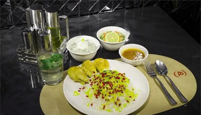 تجربه یک وعده غذایی لذیذ و اصیل ایرانی در رستوران هانی. شامل برنج زعفرانی با مرغ، ماست و خیار، سالاد، خورش و نوشیدنی خنک.