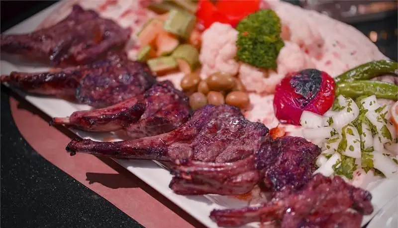 نمای نزدیک از دنده کباب (شیشلیک) لذیذ رستوران ایرانی هانی، همراه با نان تازه، فلفل کبابی و مخلفات سنتی ایرانی. یک وعده غذایی دلچسب.