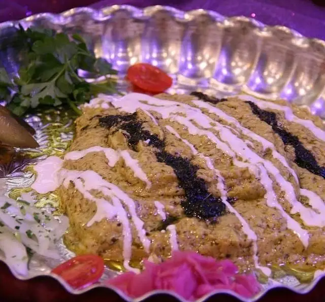 غذاهای سنتی نازخاتون: دیس زیبای کشک بادمجان با تزیین کشک و نعناع داغ، همراه با سبزیجات و ترشیجات، تجربه‌ای لذید.