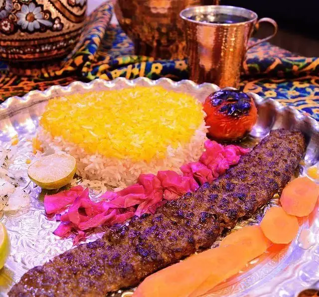 کباب کوبیده لذیذ نازخاتون با برنج زعفرانی، گوجه کبابی، ترشی و لیمو. تجربه طعم اصیل غذای ایرانی در رستوران نازخاتون.