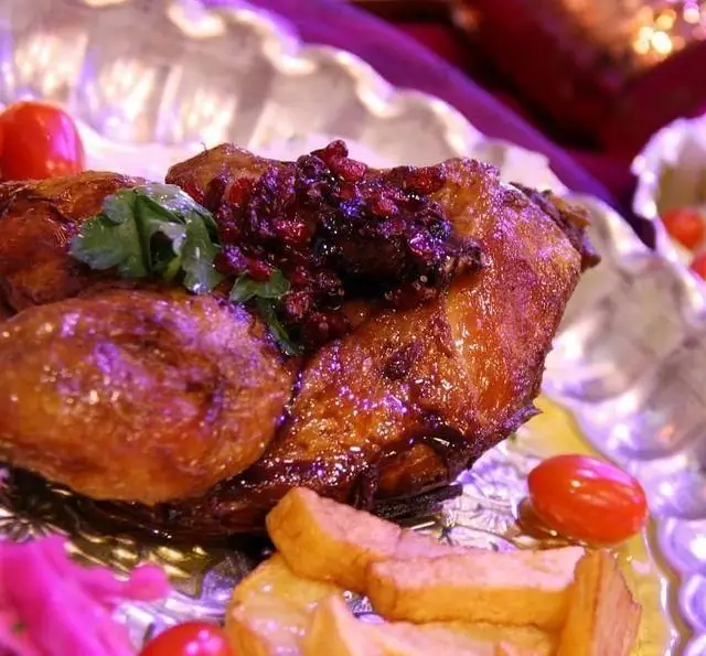 مرغ بریان لذیذ نازخاتون، یک غذای سنتی ایرانی با سس زرشک و انار، سرو شده با سبزیجات تازه و سیب‌زمینی سرخ‌کرده.