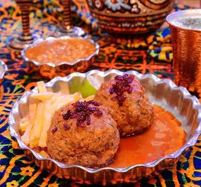 نازخاتون: کوفته تبریزی خوشمزه با سس گوجه‌فرنگی و زرشک، در کنار سیب‌زمینی و لیمو، یک غذای اصیل و سنتی ایرانی.
