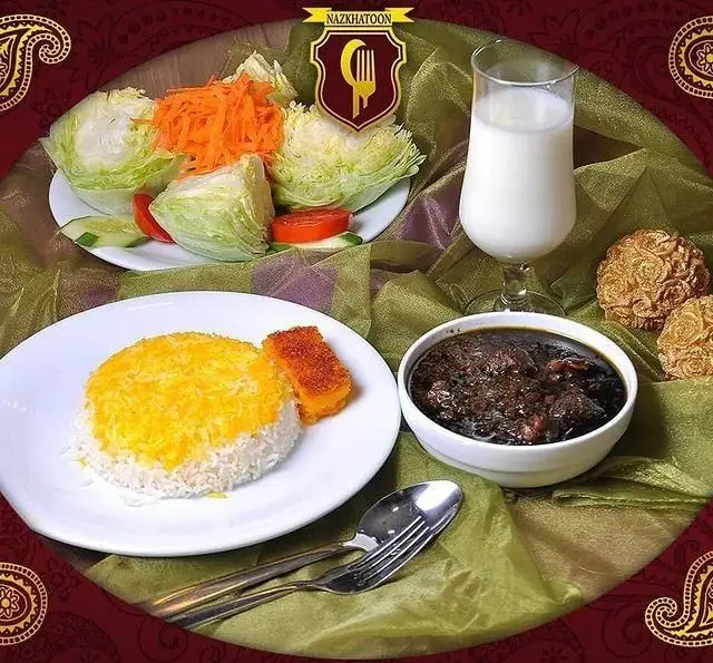 سفره ای لذیذ از رستوران نازخاتون شامل برنج زعفرانی، خورش سنتی، سالاد تازه، نوشیدنی و شیرینی های ایرانی.