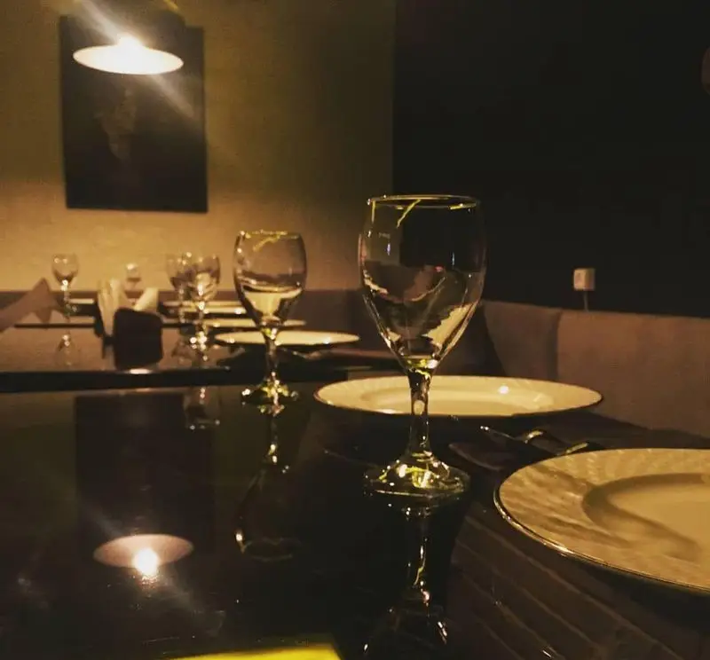 فضای داخلی دنج و دلنشین کافه سنتی ژوان در شب، با میز چیده شده، لیوان‌های شیک و نورپردازی گرم و آرامش‌بخش.