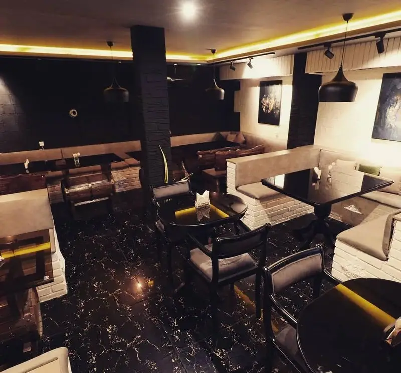 فضای داخلی دنج و شیک کافه سنتی ژوان با دکوراسیون تلفیقی مدرن و سنتی، میز و صندلی‌های راحت و نورپردازی گرم برای مشتریان.