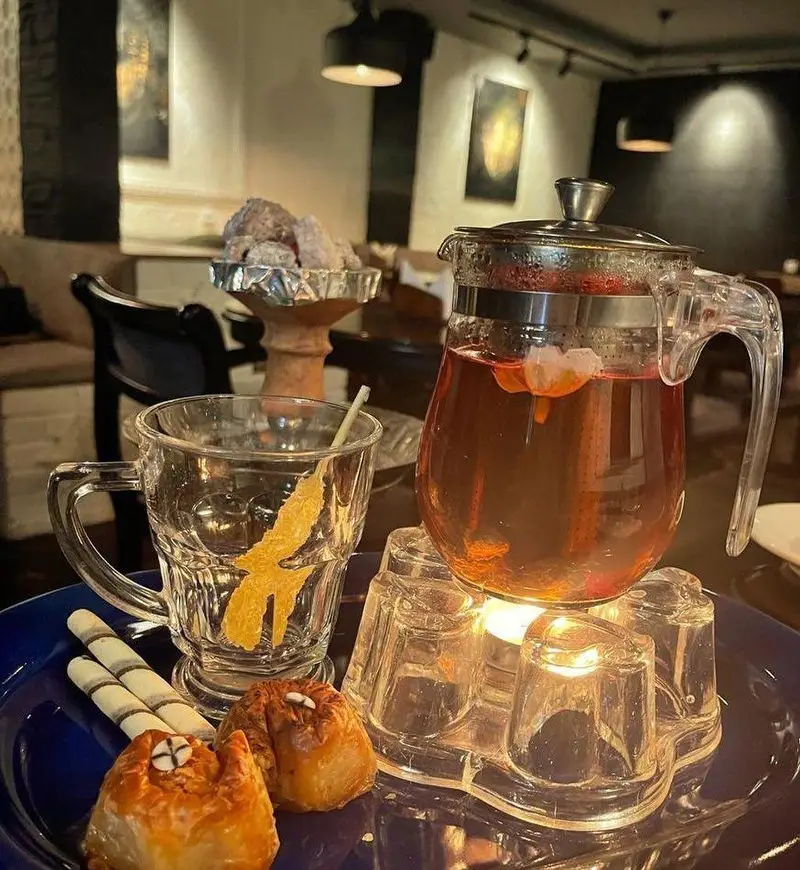 تجربه لذت‌بخش چای و دمنوش در کافه سنتی ژوان همراه با باقلوا و شیرینی در فضایی آرام و دلپذیر.