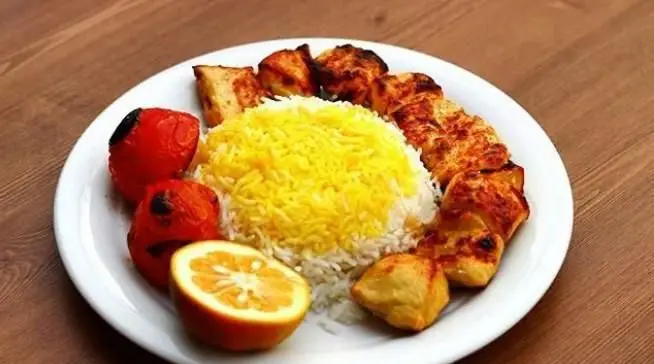 یک بشقاب چلو جوجه کباب خوشمزه و باکیفیت به همراه برنج زعفرانی معطر، گوجه کبابی و لیمو، از کبابی لیمو ریحون.