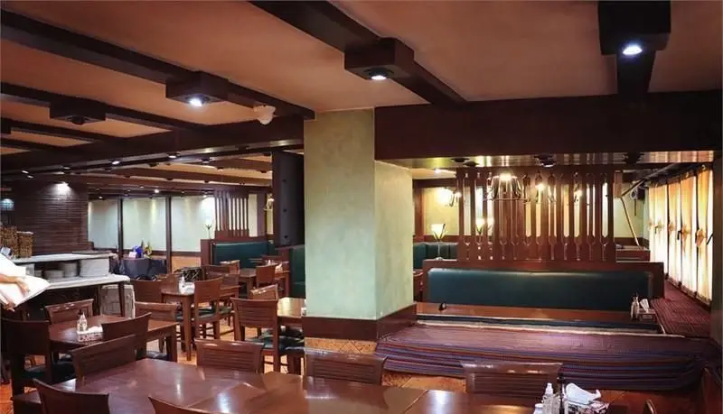 تصویری از سالن اصلی رستوران مدیا، با دکوراسیون چوبی مدرن و سنتی، میز و صندلی‌های راحت و نورپردازی محیطی دلنشین.