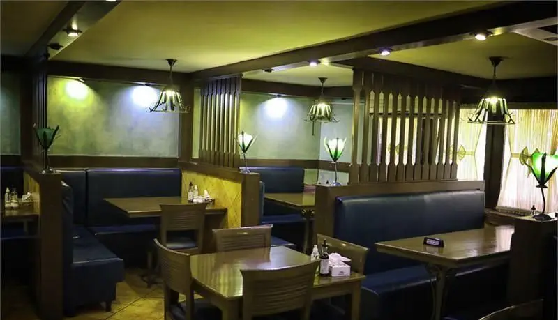 فضای داخلی دنج و دلنشین رستوران مدیا با مبلمان راحتی آبی، میزهای چوبی شیک و نورپردازی گرم، محیطی عالی برای تجربه غذاخوری.