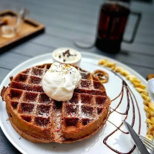 وافل خوشمزه با بستنی، پودر شکر، سس شکلات و موز در کافه و کافی شاپ لیدو پلاس. تجربه‌ای شیرین برای صبحانه یا دسر شما.