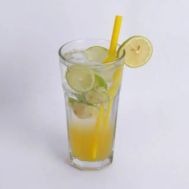 لیوان بزرگ لیموناد یخی با برش‌های تازه لیمو و نی زرد، نوشیدنی تابستانی ایده‌آل در کافه و کافی شاپ لیدو پلاس.