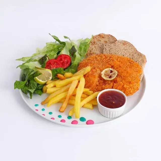 وعده غذایی لذیذ کافه لیدو پلاس شامل شنیسل سوخاری، سیب زمینی سرخ کرده طلایی، سالاد فصل و نان تست. تجربه ای دلپذیر در کافی شاپ.