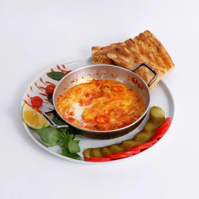 صبحانه لذیذ کافه و کافی شاپ لیدو پلاس: املت گوجه و تخم مرغ در تابه با نان تازه، ترشی، گوجه گیلاسی و لیمو.