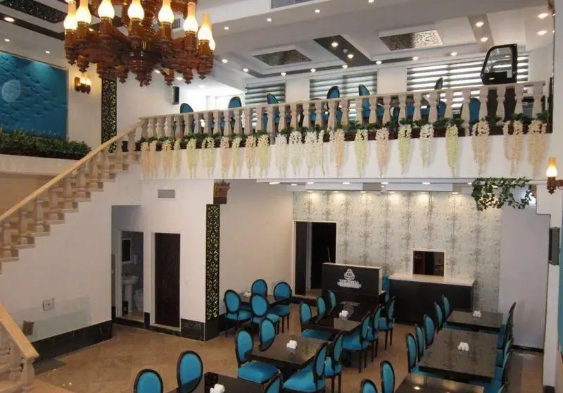 فضای داخلی شیک و دلباز کافه رستوران دلربا با دکوراسیون زیبا، میز و صندلی‌های آبی، لوستر بزرگ و بالکن دلنشین آماده پذیرایی.