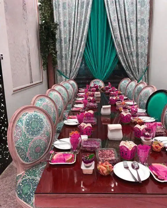 میز پذیرایی مجلل کافه رستوران دلربا با دکوراسیون صورتی و فیروزه‌ای، چیدمان جذاب غذا، میوه و دسرهای متنوع برای مهمانی.