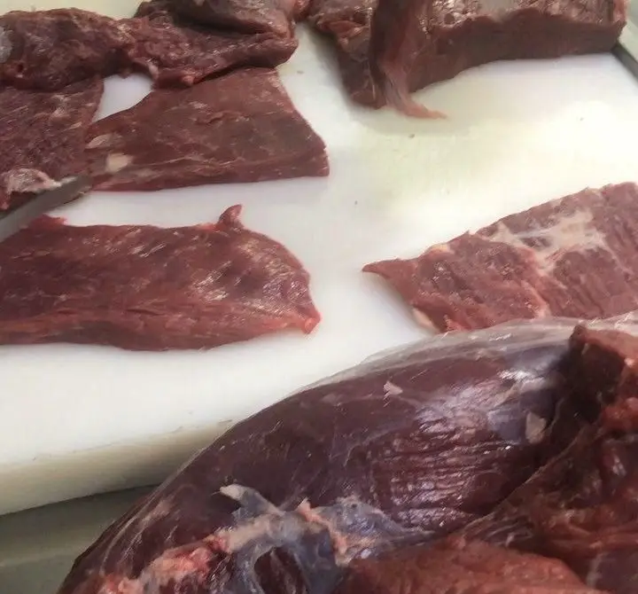 گوشت قرمز تازه و باکیفیت، برش‌خورده روی تخته سفید آشپزخانه، در حال آماده‌سازی برای غذاهای سالم و لذیذ فست فود اژدر زاپاتا.