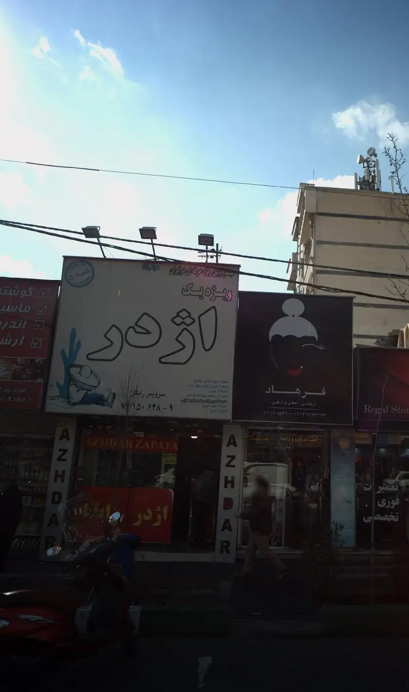 نمایی از تابلوی بزرگ فست فود اژدر زاپاتا با لوگوی جذاب و عبارت "ویژه یک" در یک روز روشن، از نمای بیرونی مغازه در خیابان.