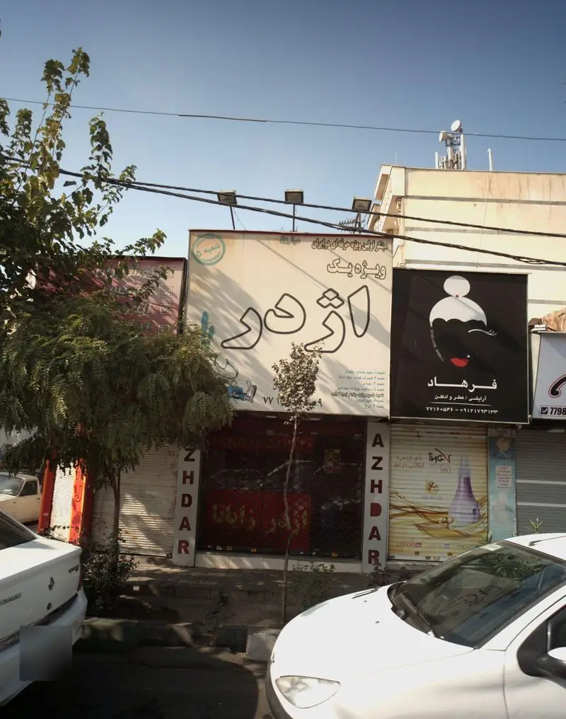 نمایی از فست فود اژدر زاپاتا در خیابان، با تابلوی بزرگ و متمایز "اژدر". تابلوهای عمودی "AZHDAR" نیز قابل مشاهده است.