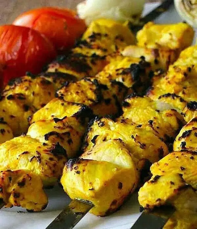 تصویری جذاب از جوجه کباب زعفرانی خوشرنگ جگرسرای کلبه صحرا همراه با گوجه کبابی، بهترین انتخاب برای یک وعده غذایی دلپذیر و باکیفیت.