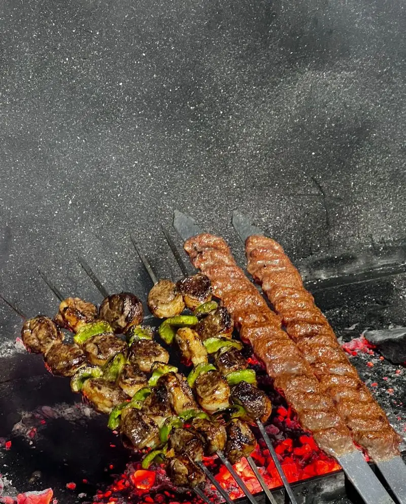 کباب کوبیده و سیخ‌های گوشت با فلفل جگرسرای کلبه صحرا در حال کباب شدن روی ذغال داغ. غذایی اصیل و خوشمزه.
