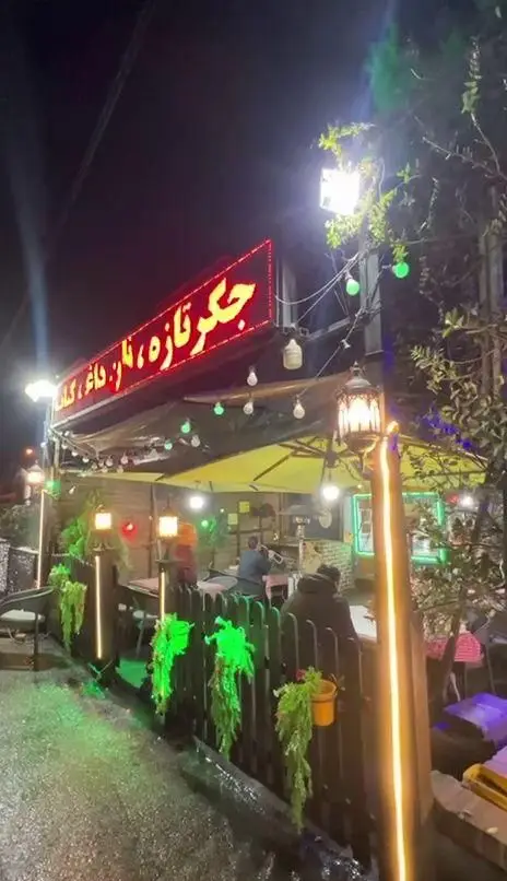 منظره‌ای دلنشین از جگرسرای کلبه صحرا در شب، با تابلو 'جگر تازه، نان داغ، کباب داغ'، فضای باز و نورپردازی جذاب و دلپذیر.