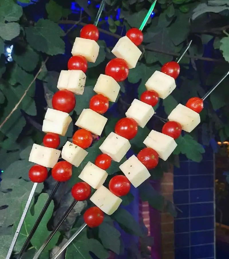 سیخ‌های خوش‌طعم و رنگارنگ مزه با گوجه گیلاسی تازه و پنیر مکعبی، پیش‌غذایی ایده‌آل برای شروع در جگرسرای کلبه صحرا.