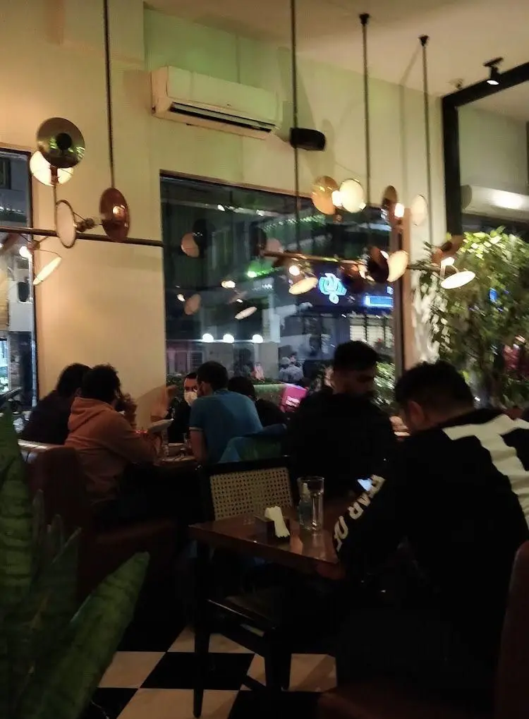 نمای داخلی شیک رستوران جو، فضایی دنج با مشتریان در حال غذا خوردن، دکوراسیون مدرن و نورپردازی جذاب، تجربه غذایی دلپذیر.