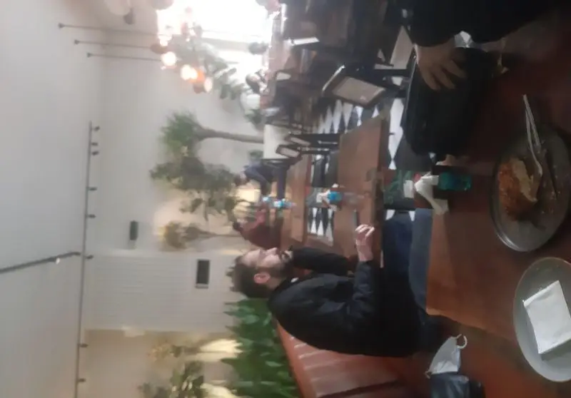 نمایی از فضای داخلی رستوران جو با دکوراسیون خاص و فضای سبز، مشتریان در حال صرف غذا و لذت بردن از محیط دلنشین و آرام.