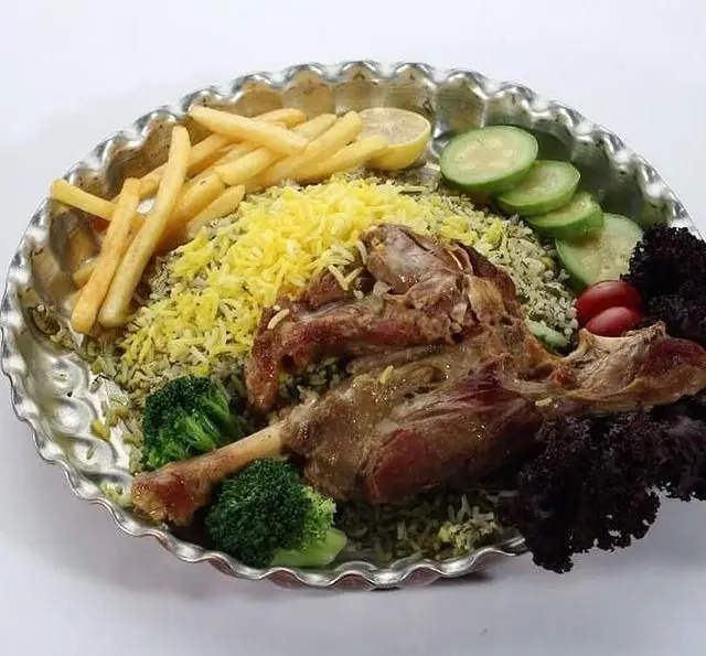 دیس ویژه سبزی پلو با ماهیچه لذیذ بره، پلوی زعفرانی، سیب زمینی سرخ کرده، بروکلی و مخلفات تازه در کافی شاپ فوکورت آرتمیس.