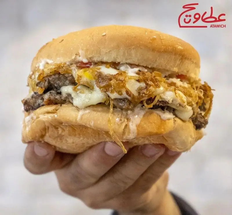 برگر خاص عطاویچ فردوس غرب: همبرگر دوبل با پنیر ذوب شده، تخم مرغ نیمرو و پیاز کاراملی بر روی نان تازه، یک تجربه لذیذ و دلپذیر.