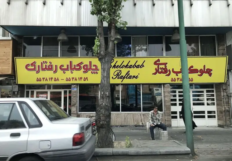 تصویری از نمای خارجی رستوران چلوکباب رفتاری، تابلوی زرد رنگ، شماره تماس و محیط شهری. ارائه دهنده بهترین غذای ایرانی و چلوکباب در تهران.