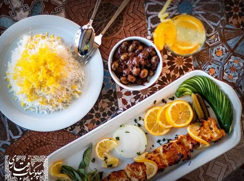 چیدمان زیبای چلو جوجه کباب زعفرانی رستوران رفتاری با برنج، خورش سنتی و نوشیدنی تازه، آماده برای ناهار یا شام دلپذیر؛ غذای اصیل ایرانی.
