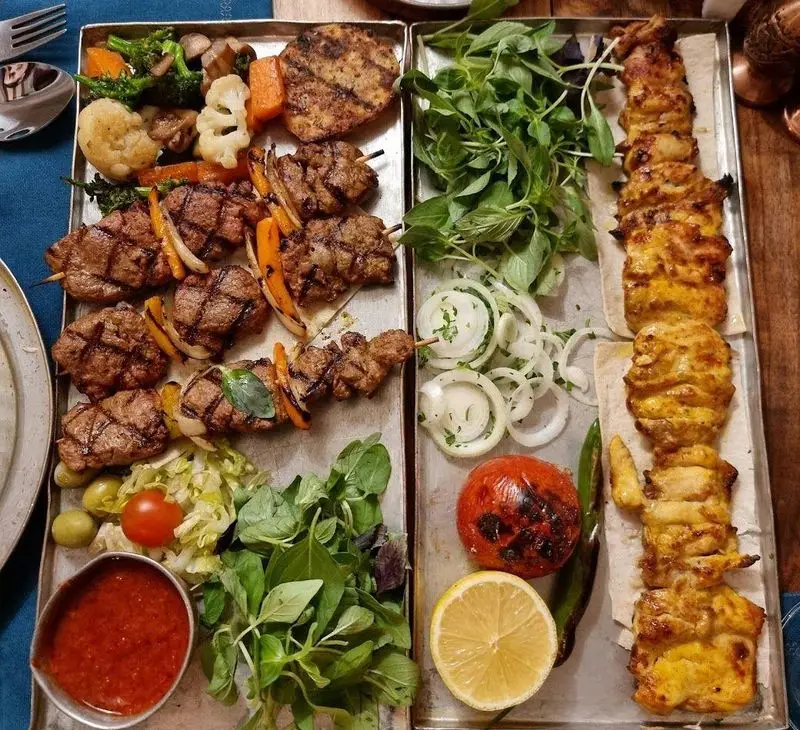 مجلل ترین سینی کباب میکس رستوران مس توران شامل جوجه کباب، کباب چنجه، سبزیجات کبابی، سس مخصوص و سبزیجات تازه.