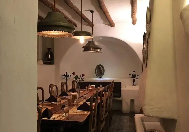 فضای داخلی دلنشین و دکوراسیون سنتی رستوران مس توران با میز چوبی بلند چیده شده برای شام، نورپردازی گرم و محیطی خاص.