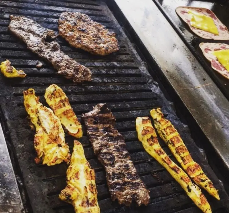 تصویری از گریل شدن گوشت، مرغ و همبرگر تازه برای ساندویچ‌های خوشمزه در فست فود اژدر زاپاتا، به همراه ژامبون و پنیر آماده برای سرو.