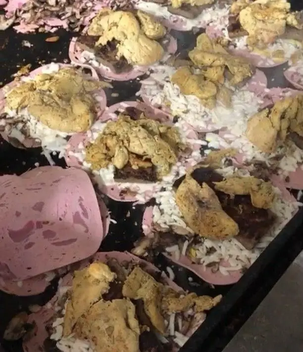 آماده‌سازی فست فود اژدر زاپاتا: ژامبون صورتی، پنیر، گوشت و مرغ طعم‌دار روی گریل داغ برای ساندویچ‌های پرملات.