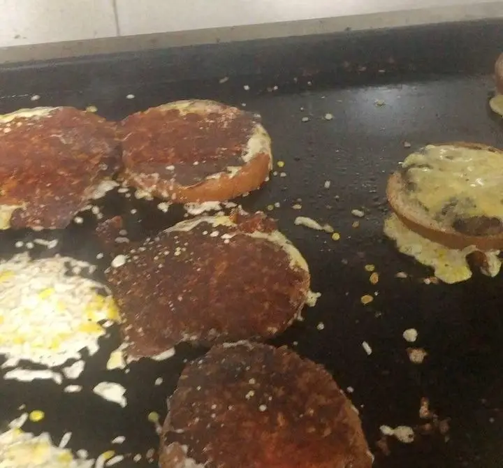 آماده سازی ساندویچ‌های برگر لذیذ فست فود اژدر زاپاتا روی صفحه گریل داغ، با پنیر آب شده و نان تست شده، بسیار تازه.