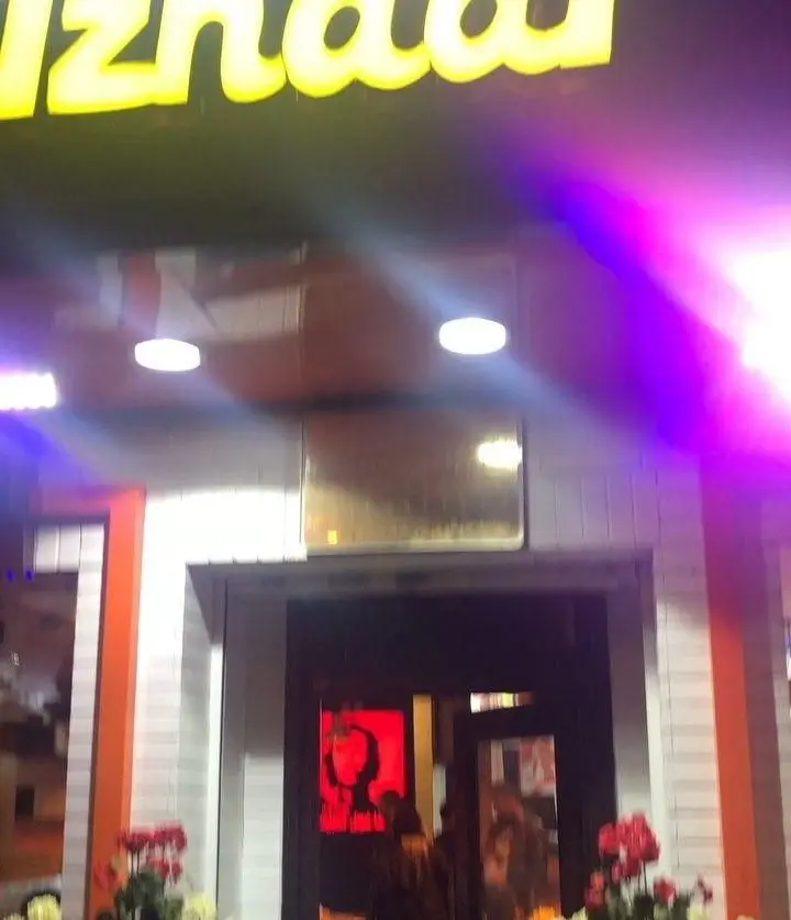 نمای شبانه و پرنور فست فود اژدر زاپاتا با تابلوی نئونی زرد درخشان. ورودی جذاب و دعوت‌کننده برای تجربه بهترین غذای سریع.