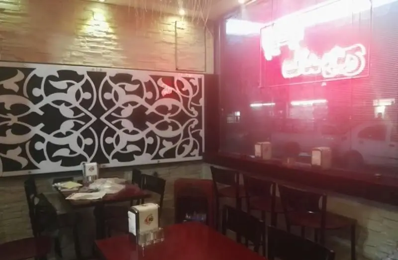 نمای داخلی شیک فست فود پیتزا شهرک با دکوراسیون مدرن، میز و صندلی‌های راحت و محیطی دلپذیر برای مشتریان گرامی.