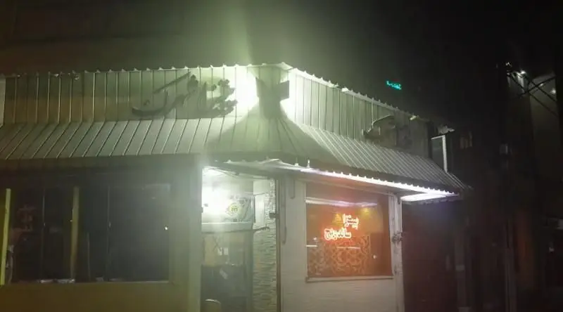 نمای بیرونی فست فود پیتزاشهرک در شب با تابلوی نئون روشن. بهترین پیتزا و فست فود در شهرک را تجربه کنید.