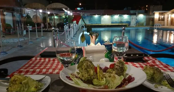 نمای شبانه از محیط دلپذیر رستوران فرسکا با میز شام کنار استخر روشن، مناسب برای تجربه‌ای به یادماندنی در فضای باز.